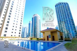 un hôtel avec une piscine en face de grands bâtiments dans l'établissement Rb Hostel Jbr, à Dubaï