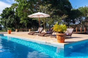 a patio with chairs and an umbrella next to a pool at Casa Sol Búzios in Armacao dos Buzios
