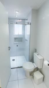 a white bathroom with a shower and a toilet at Apartamento 3 quartos em Pitangueiras in Guarujá