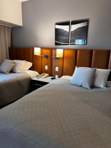 um quarto de hotel com duas camas e um telefone em Suite 505 Wynd Berrini WTC - SP em São Paulo