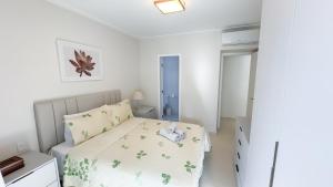 a white bedroom with a bed and a night stand at Apartamento 3 quartos em Pitangueiras in Guarujá