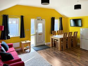 sala de estar con paredes amarillas, mesa y sofá en The Stables en Forncett Saint Mary