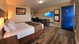 a hotel room with a bed and a blue door at Maple Leaf Inn & Suites in Kincardine