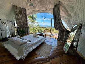 a bedroom with a bed and a large window at Domos Mirador Romantic Private Honeymoon Glamping in Miramar
