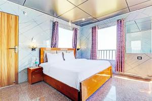 sypialnia z dużym łóżkiem i oknami w obiekcie OYO Hotel Neilkanth w mieście Dhanaulti