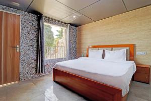 sypialnia z dużym łóżkiem i oknem w obiekcie OYO Hotel Neilkanth w mieście Dhanaulti