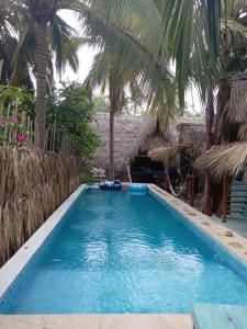 a swimming pool with palm trees in a resort at El Puente in El Paredón Buena Vista