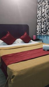 a bed with two red pillows on top of it at Misty Stay by Le Apex in Ooty