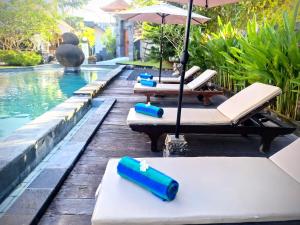 - une rangée de chaises longues avec parasols à côté de la piscine dans l'établissement Bambu Lokha Guest house, Gianyar Bali, à Ubud