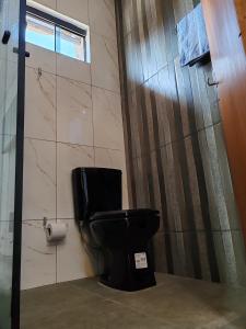 La salle de bains est pourvue de toilettes noires et d'un rouleau de papier toilette. dans l'établissement España Stay, à Ciudad del Este