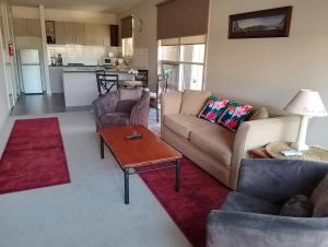 a living room with a couch and a table at Lovely 2 bedroom apartment across from Shepp Lake. in Shepparton