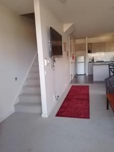 a living room with a staircase and a red rug at Lovely 2 bedroom apartment across from Shepp Lake. in Shepparton