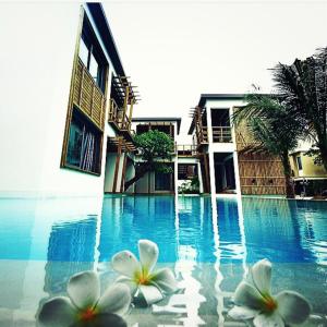 dos flores blancas sentadas en la parte superior de una piscina en Paragon Inn, en Lat Krabang