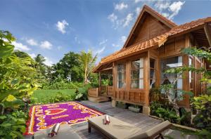 ein Holzhaus mit einem Teppich davor in der Unterkunft The Kalyana Ubud Resort in Ubud