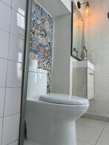 baño con aseo y pared de mosaico en Hotel Boutique Casona los Pavorreales, en Durango