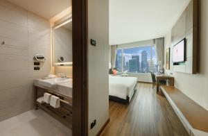 a bathroom with a bed and a sink in a room at Eastin Grand Hotel Sathorn in Bangkok