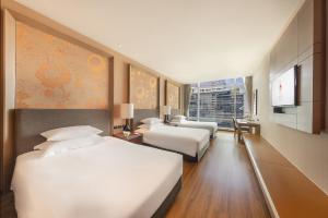 a hotel room with two beds and a television at Eastin Grand Hotel Sathorn in Bangkok