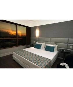 a hotel room with a large bed with blue pillows at Flat BH Savassi in Belo Horizonte +16 photos