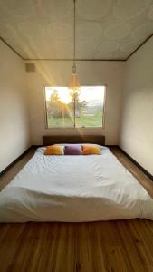 a large bed in a room with a window at Sound Garden Biei, Cricket in Biei