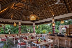 un ristorante con tavoli, sedie e luci di The Kalyana Ubud Resort ad Ubud