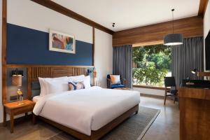 Un dormitorio con una gran cama blanca y una ventana en voco Jim Corbett, an IHG Hotel, en Rāmnagar