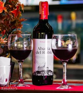 a bottle of wine next to two glasses of red wine at Hotel Eduards Suite in Macuto