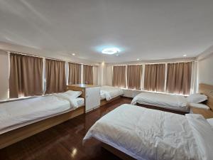 a bedroom with three beds and a window at Moncozy guesthouse in Ulaanbaatar