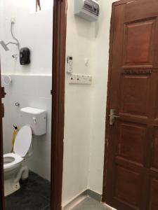 uma casa de banho com um WC e uma porta de madeira em Tiny House Idaman Kuala Terengganu with Private House em Kuala Terengganu