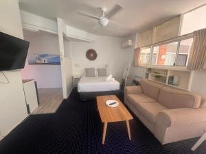 sala de estar con sofá y cama en OCEAN BREEZE MOTEL, en Port Macquarie