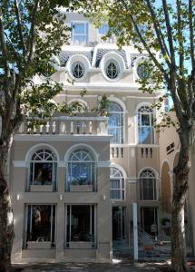 a white building with trees in front of it at Rendez Vous Hotel Buenos Aires in Buenos Aires