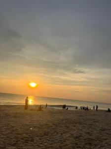 un grupo de personas en una playa al atardecer en Marari kallyani beach homestay, en Mararikulam