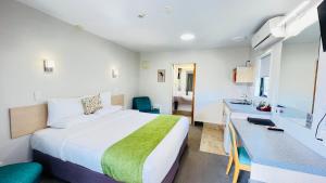 ein Hotelzimmer mit einem großen Bett und einem Schreibtisch in der Unterkunft Bella Vista Motel Whangarei in Whangarei