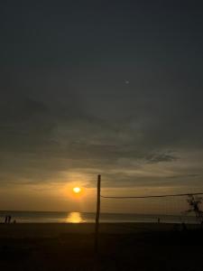 una puesta de sol en una playa con una valla en primer plano en Marari kallyani beach homestay, en Mararikulam