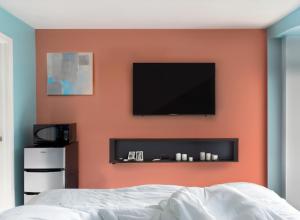 1 dormitorio con pared de color naranja y TV de pantalla plana en Granby Motel en South Hadley