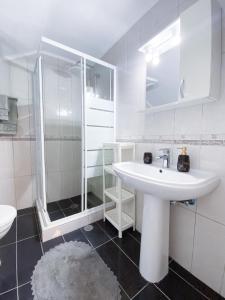 La salle de bains blanche est pourvue d'un lavabo et d'une douche. dans l'établissement Pigadia Central, à Karpathos