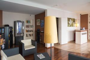 a living room with a couch and a chair and a lamp at Hôtel Jaurès in Toulon