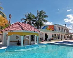 a building with a swimming pool next to a house at Pelican Inn at Las Dunas Chelem in Chelem