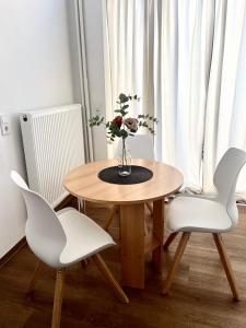 a wooden table with white chairs and a vase with flowers at Suite One Langestr II in Varel