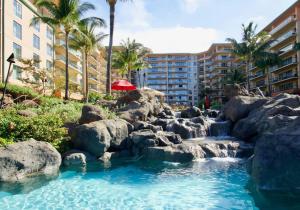 a swimming pool with a waterfall in a resort at Ocean View One Bedroom at Honua Kai!! in Lahaina