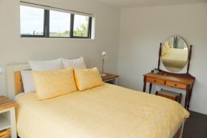 The Stargazer - Mangawhai Heads Holiday Home في مانجاواي: غرفة نوم مع سرير ومرآة
