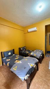 two beds in a room with yellow walls at Country house Pulai Holiday Village in Gua Musang