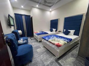 1 dormitorio con 2 camas y silla azul en Lasani 1 Hotel, en Lahore