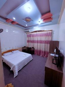 Un dormitorio con una cama grande y una mesa y publicidad. en Phạm Gia Hotel HG - by BAY LUXURY, en Ha Giang