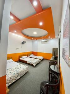 Tres camas en una habitación con techo naranja. en Phạm Gia Hotel HG - by BAY LUXURY, en Ha Giang
