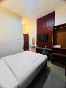 1 dormitorio con 1 cama y escritorio con TV en House of Bedjo en Demangan