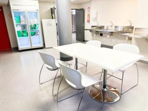United Auckland في أوكلاند: طاولة بيضاء وكراسي في غرفة