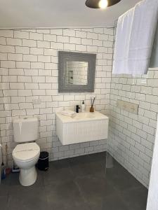 a white bathroom with a toilet and a sink at Table Hill Cottage in Daylesford