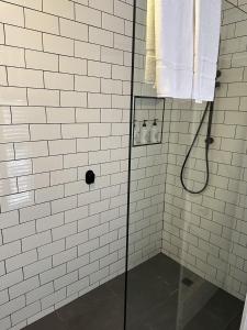 a white tiled shower with a glass shower backdoor at Table Hill Cottage in Daylesford