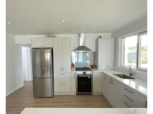 a kitchen with white cabinets and a stainless steel refrigerator at Oneroa Hillcrest - Waiheke Escapes in Blackpool