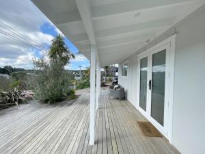 a porch of a white house with a wooden deck at Oneroa Hillcrest - Waiheke Escapes in Blackpool